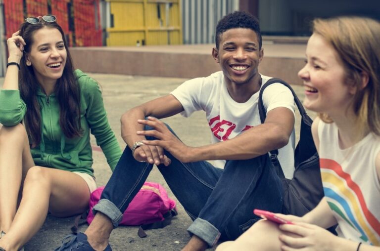 Three teenage youths sit in a courtyard laughing