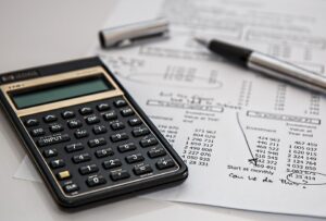 A calculator and pen sit atop an accounting paper