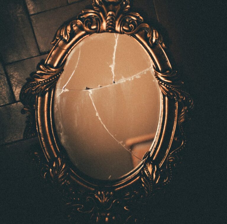 A cracked mirror with an ornate copper-colored frame.