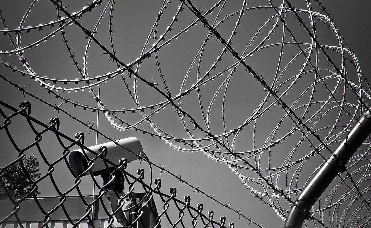 There is a black and white image of barbed wire and a metal fence.