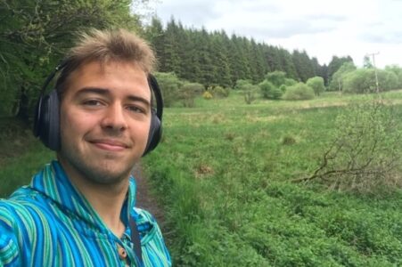 CCL intern André wearing headphones, standing in a green field