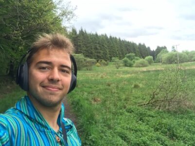 CCL intern André wearing headphones in a green field
