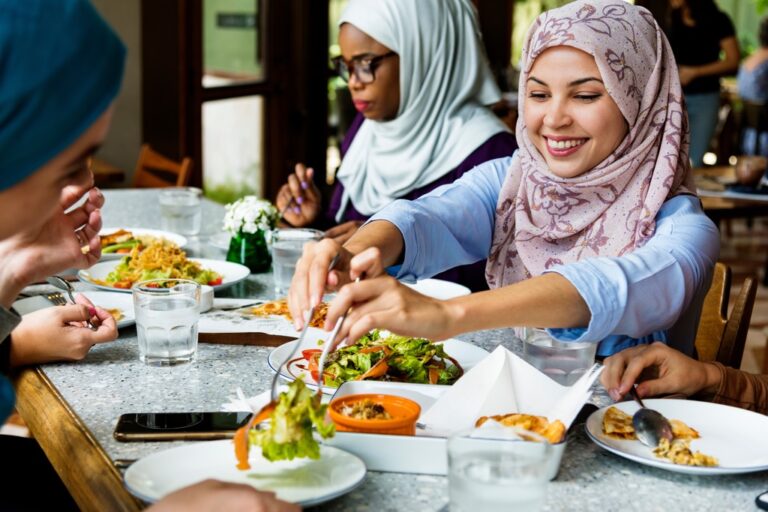 A group of youths in headscarves eating a meal