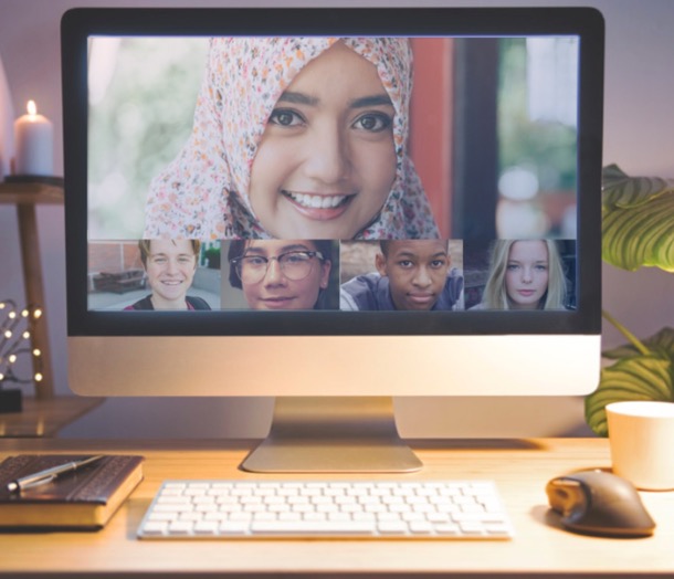 A desktop computer with a video call of five youths on the screen