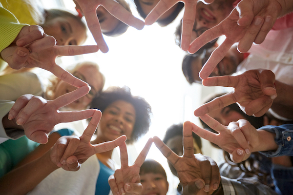 A group of youths in a circle making peace signs with their hands