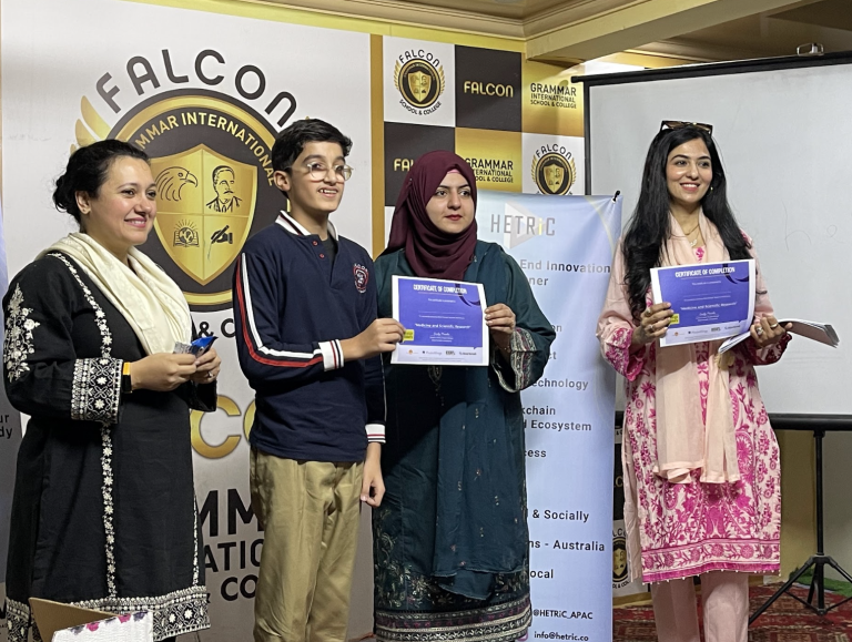 Young male student receives his certificate from a teacher and HETRiC representatives