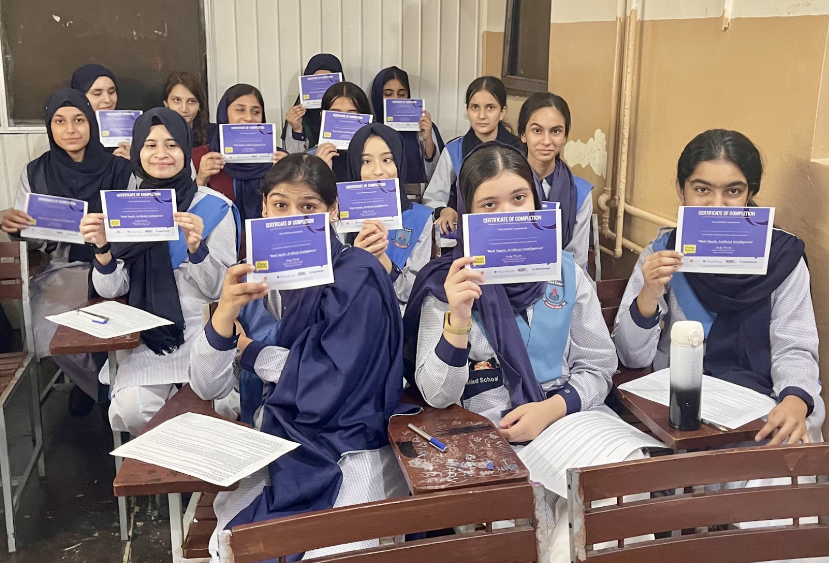 Classroom of girls holding Global Nomads Certificates